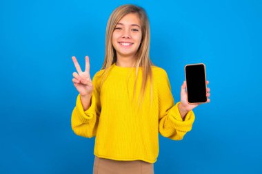 Mavi arka planda sarı süveter giyen beyaz bir kız. Elinde Ziyaretçi işareti gösteren modern bir cihaz var. 