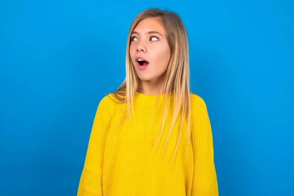 Shocked Caucasian Teen Girl Wearing Yellow Sweater Blue Studio Background — Stock Photo, Image