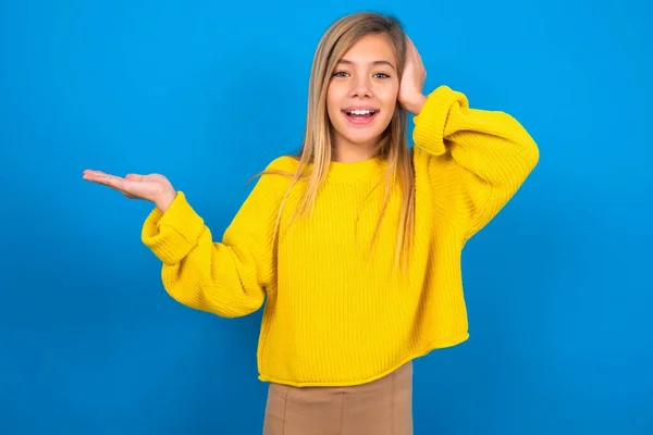 Sorprendido Caucásico Adolescente Chica Usando Amarillo Suéter Sobre Azul Estudio —  Fotos de Stock