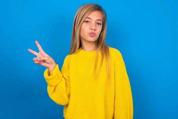 girl makes peace gesture keeps lips folded shows v sign. Body language concept
