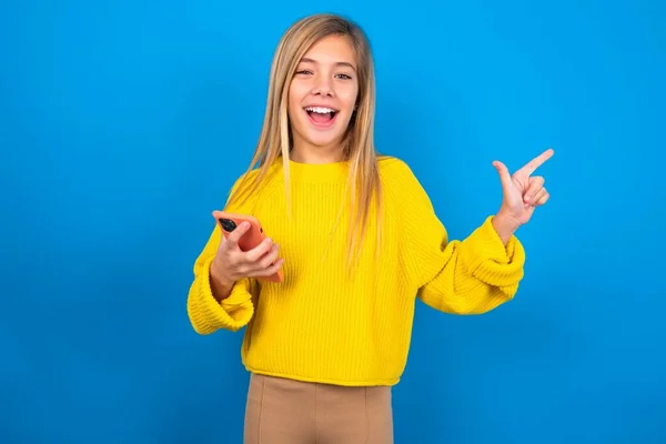 Verblüfftes Kaukasisches Teenie Mädchen Gelbem Pullover Über Blauem Studiohintergrund Hält — Stockfoto