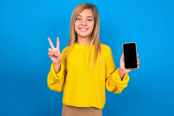 Caucasian Teen Girl Wearing Yellow Sweater Blue Studio Background Holding — Stock Photo, Image