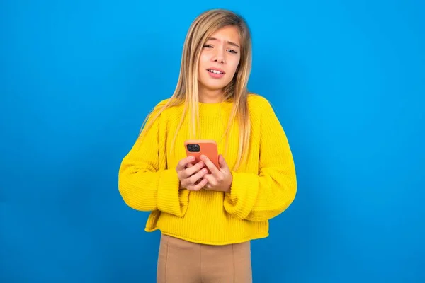 Photo Astonished Caucasian Teen Girl Wearing Yellow Sweater Blue Studio — Stock Photo, Image