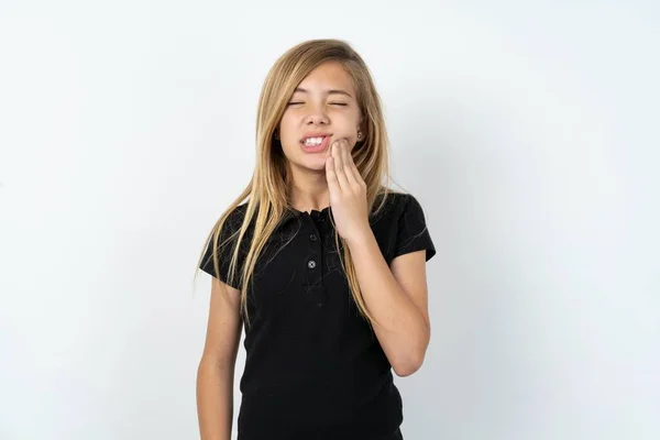 歯痛や歯の病気のために痛みを伴う表情で手を触れる白い壁の上に黒いTシャツを着ている美しい白人十代の少女 — ストック写真
