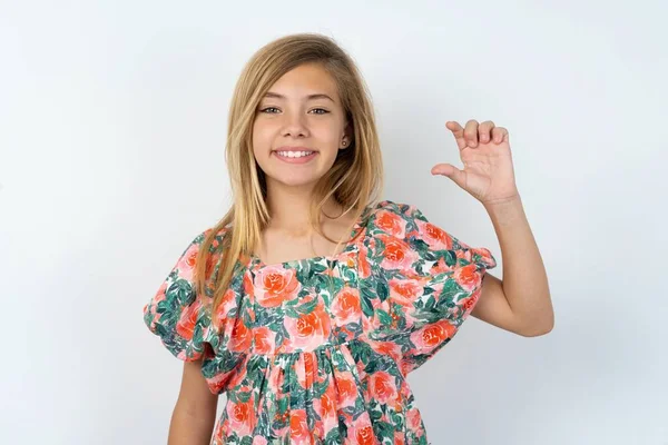 漂亮的高加索少女 身穿花衬衫 穿过白墙 面带微笑 自信地做手势 手拿着小尺寸的标志 手拿着手指 手拿着相机 计量概念 — 图库照片