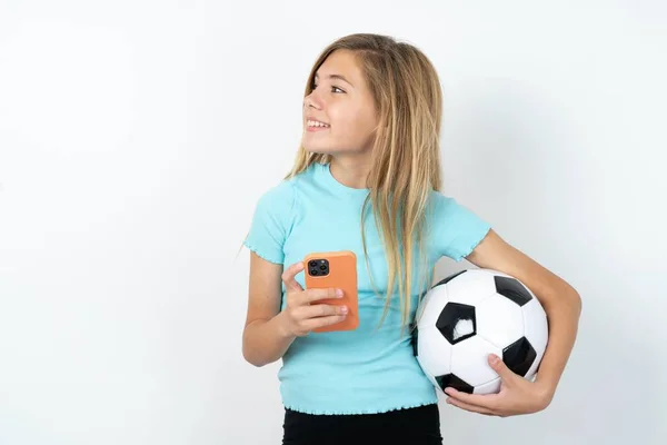 サッカーボールと白い背景の上の新しい細胞を遠ざけている若いケルシナガール — ストック写真