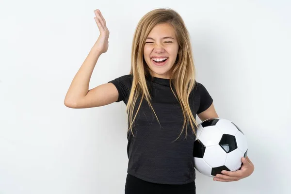 身穿运动服的少女拿着足球冲过白墙发疯了 因为糟糕的情况使她头晕脑胀 — 图库照片