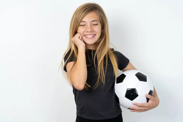 身穿运动服的少女欢快地笑着 拿着足球穿过白墙 想象着令人愉快的事 模仿空间 快乐的情感概念 — 图库照片