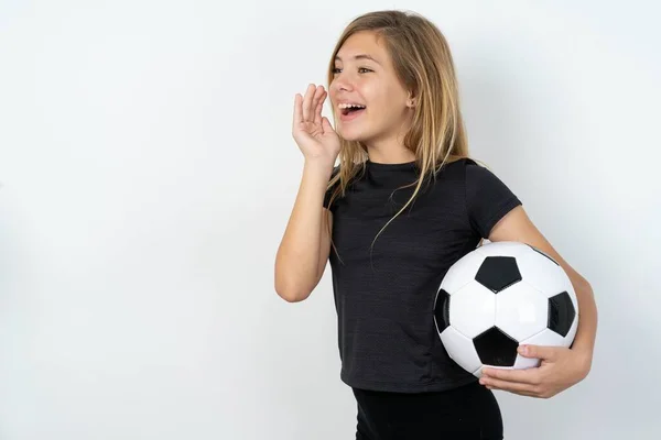 身穿运动服的少女拿着足球冲过白墙 空空如也 手牵着手尖叫或打电话给某人 — 图库照片