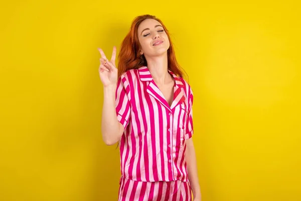 Joven Mujer Pelirroja Vistiendo Pijama Rosa Sobre Fondo Amarillo Del — Foto de Stock