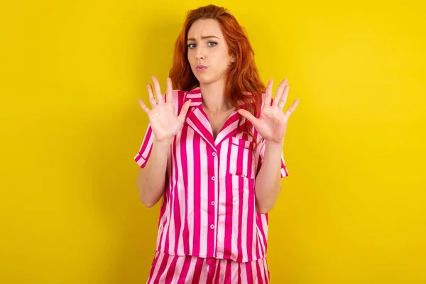 Jonge Roodharige Vrouw Draagt Roze Pyjama Gele Studioachtergrond Die Handpalmen — Stockfoto