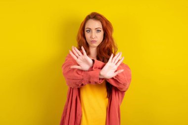 Sarı stüdyo arka planında duran güzel kızıl saçlı kadın reddedilmiştir. Kollarını kavuşturur, avuç içleri boştur, kızgın bir yüz ifadesi takınır..