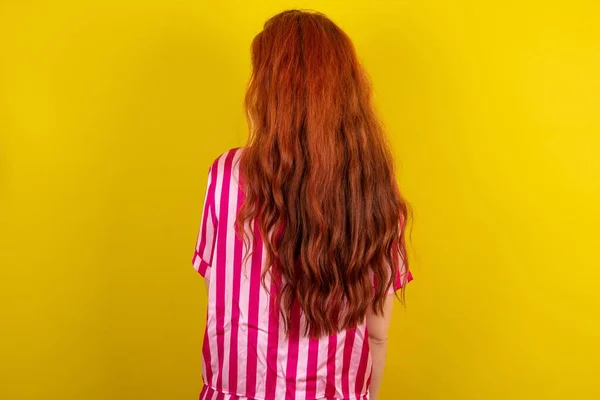 Молодая Рыжая Женщина Розовом Пижаме Фоне Жёлтой Студии Видом Заднюю — стоковое фото