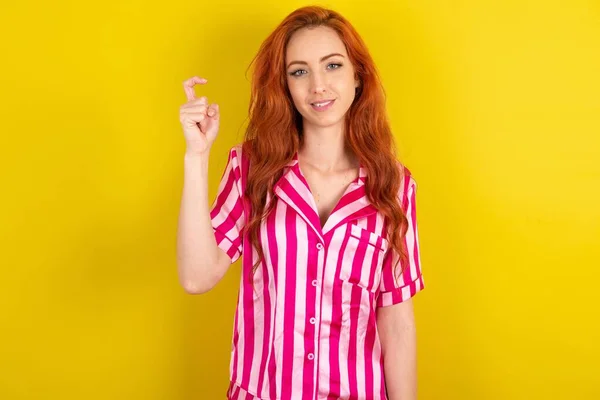 黄色いスタジオの背景にピンクのピンクのパジャマを身に着けている若い赤毛の女性は 中国語で指のナンバー9を指で指を指します — ストック写真