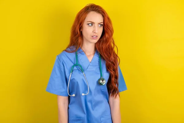 Young Red Haired Doctor Woman Yellow Studio Background Stares Aside — Stock Photo, Image