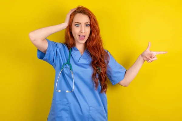 Surprised Young Red Haired Doctor Woman Yellow Studio Background Pointing — Stock Photo, Image