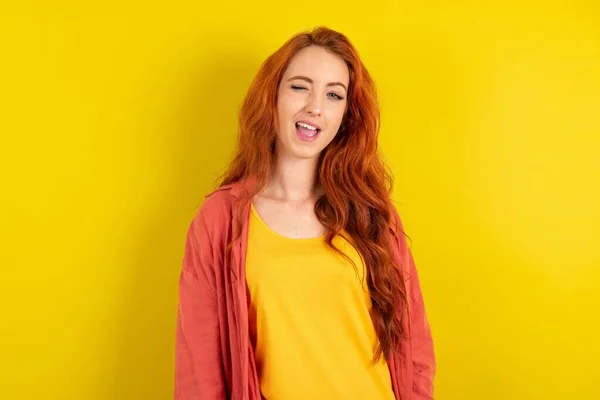 美しい赤毛の女性は セクシーな表情 陽気で幸せな顔でカメラを見ながら黄色のスタジオの背景の上に立っています — ストック写真