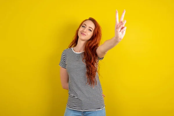 Red Haired Woman Wearing Striped Shirt Yellow Studio Background Directs — Stock Photo, Image