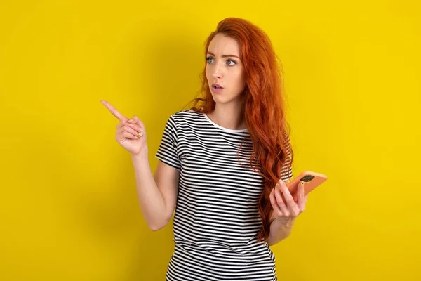 Verbaasde Rood Harige Vrouw Draagt Gestreept Shirt Gele Studio Achtergrond — Stockfoto