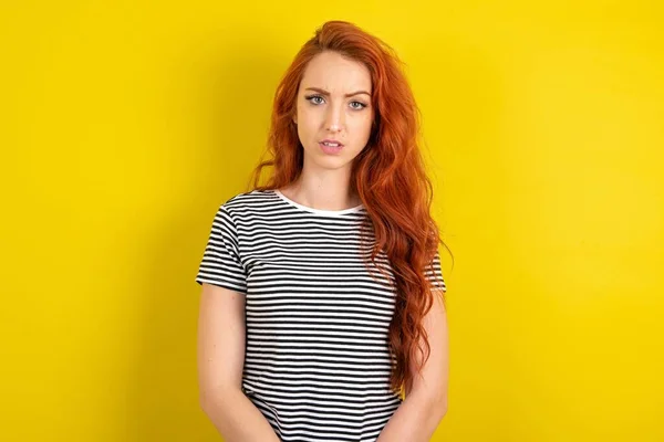 赤毛の女性はイエロースタジオの背景にストライプのシャツを着て 広告を示す指で指を指し 驚きの顔と口を開きました — ストック写真