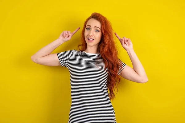 髪を示す黄色いスタジオの背景にストライプのシャツを着ている陽気な赤毛の女性 — ストック写真