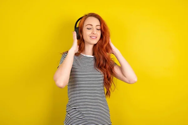 Red Haired Woman Wearing Striped Shirt Yellow Studio Background Headphones — Stock Photo, Image