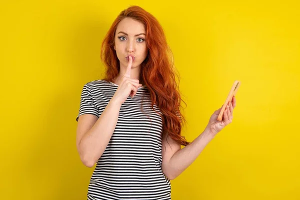 Red Haired Woman Wearing Striped Shirt Yellow Studio Background Holding — Stock Photo, Image
