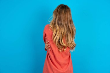 Sarışın kadın, tişört giyip kendine sarılıyor, mutlu ve pozitif bakıyor. Sevgi ve özgüven.