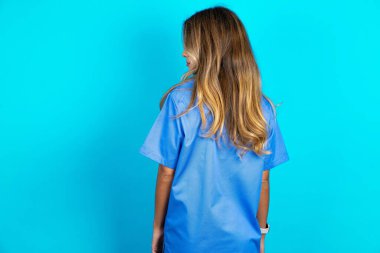 Mavi stüdyo arka planında duran güzel bir doktor kadının arka yüzü. Stüdyo Çekimi.