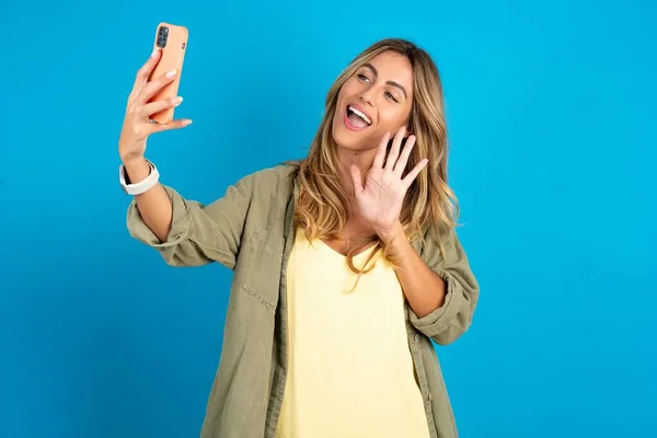 Beautiful Blonde Woman Wearing Overshirt Blue Background Holds Modern Mobile — Stock Photo, Image