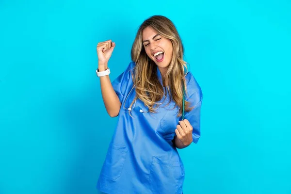 Piękna Lekarz Kobieta Stojąca Nad Niebieskim Tle Studio Bardzo Szczęśliwy — Zdjęcie stockowe