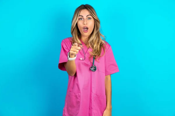 Σοκαρισμένη Όμορφη Γιατρός Γυναίκα Στέκεται Πάνω Από Μπλε Στούντιο Σημεία — Φωτογραφία Αρχείου
