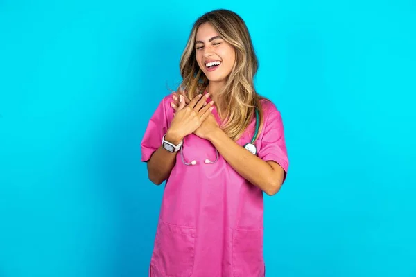 白人女性医師 ピンクの医学の制服にステスコープは幸せを表現し 喜んで笑い 心に手を保ちます — ストック写真