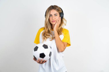 Genç ve güzel bir kadının futbol topunu beyaz arka planda tutarken çekilmiş fotoğrafı. Taze, pürüzsüz cilt dokunuşunun tadını çıkar.
