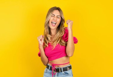 Sarı arka planda pembe etek giyen, kendinden geçmiş sarışın genç kadın yüksek sesle bağır.