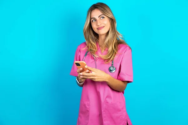 Die Kaukasische Ärztin Pinkfarbener Arztuniform Mit Stethoskop Hält Ein Mobiltelefon — Stockfoto