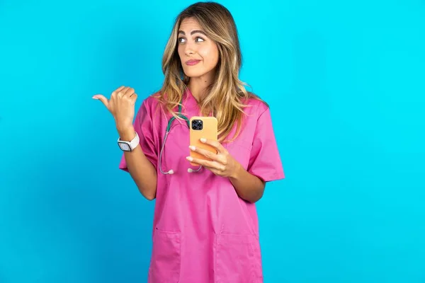 Kaukasisk Kvinna Läkare Rosa Medicinsk Uniform Med Stetoskop Pekar Tummen — Stockfoto