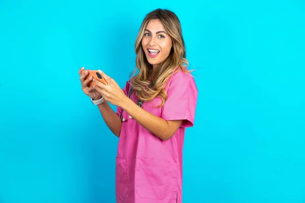 漂亮的瘾君子 快乐的高加索女医生 身穿粉色军服 带听诊器 用小玩意玩网络游戏 — 图库照片