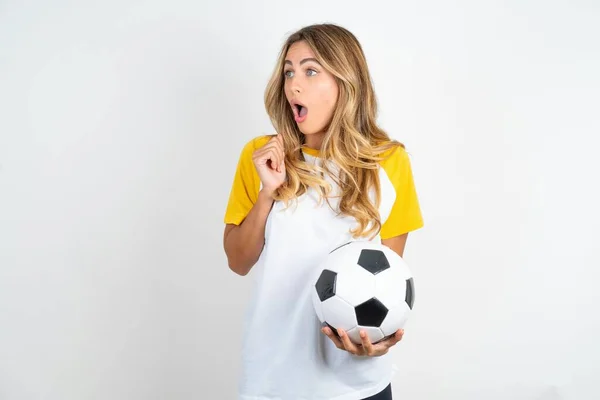 Zdumiewające Młoda Piękna Kobieta Trzyma Piłkę Nożną Białym Tle Patrzy — Zdjęcie stockowe