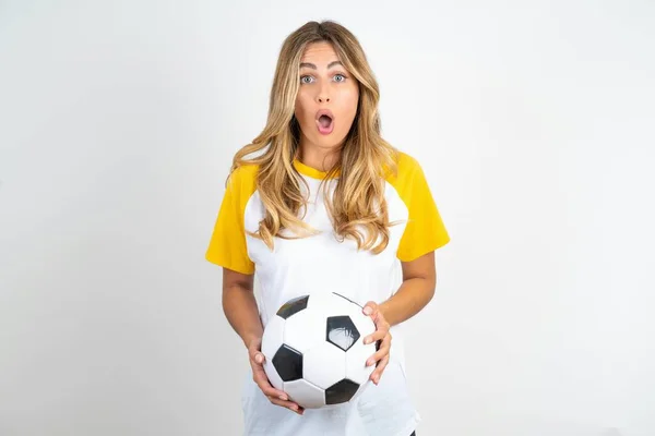 Chocado Jovem Bela Mulher Segurando Bola Futebol Sobre Olhos Fundo — Fotografia de Stock