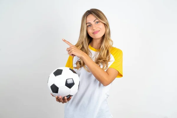 Młoda Piękna Kobieta Trzymająca Piłkę Nożną Nad Białym Tle Wskazuje — Zdjęcie stockowe