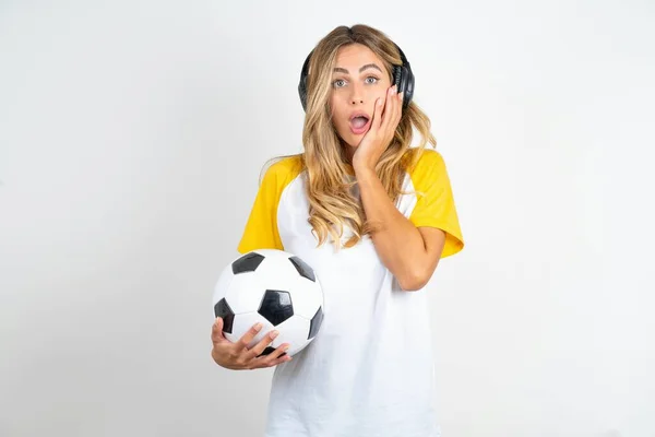 Wstrząśnięta Młoda Piękna Kobieta Trzyma Piłkę Nożną Nad Białym Tłem — Zdjęcie stockowe