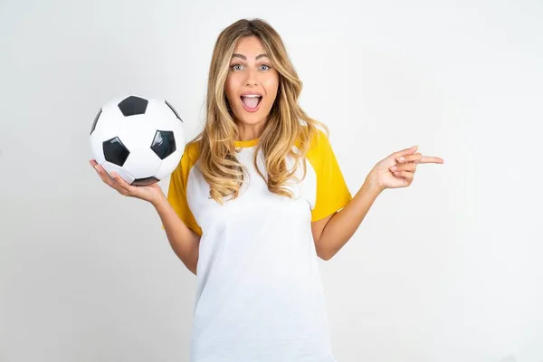 Zaskoczona Piękna Kobieta Nosi Koszulkę Piłkarską Białym Tle Wskazując Puste — Zdjęcie stockowe