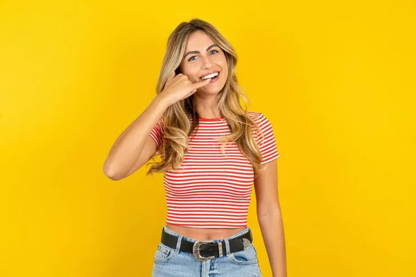 Sarı Arka Planda Çizgili Tişört Giyen Gülümseyen Genç Bir Kadın — Stok fotoğraf