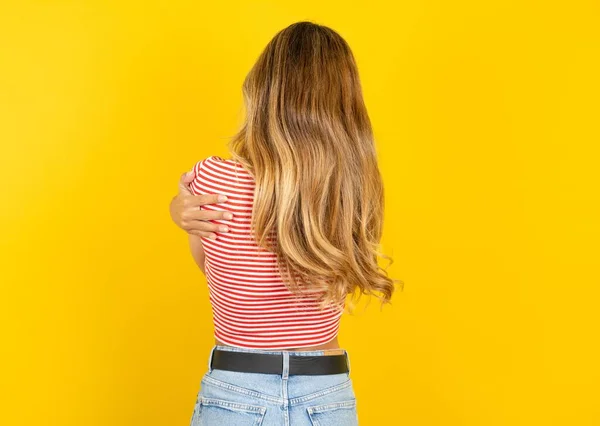 年轻美丽的金发女人穿着条纹T恤 披着黄色的工作室背景 欢快而积极地拥抱着自己 自爱和自我照顾 — 图库照片