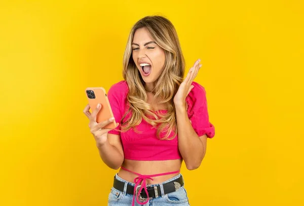 Naštvaná Blondýna Mladá Žena Růžovém Tričku Žlutém Pozadí Křičí Telefonu — Stock fotografie