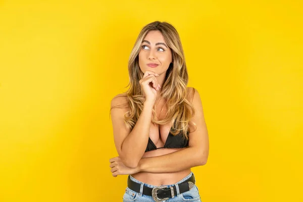 Sarı Arka Planda Bikini Giyen Düşünceli Genç Sarışın Kadın Çenesini — Stok fotoğraf