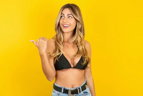 Sarı Arkaplan Üzerine Bikini Giyen Güzel Sarışın Kadın Reklamları Gösteriyor — Stok fotoğraf