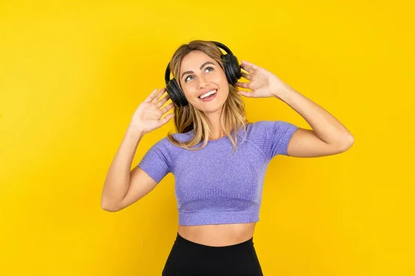 Joyful Young Woman Wearing Sportswear Yellow Studio Background Listens Favorite — Stock Photo, Image