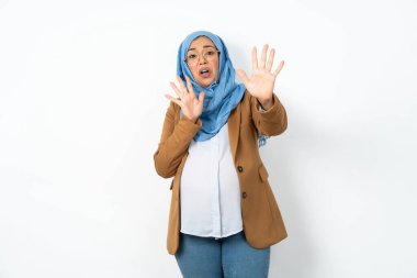 Başörtüsü takan hamile Müslüman kadın korku ifadesinden korkmuş ve dehşete düşmüş. El hareketini durdur, şok içinde bağır. Panik konsepti.
